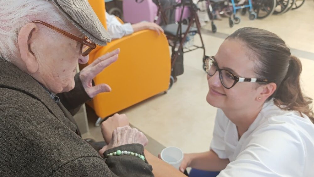 Humanidad en la Residencia de Mayores Profesionales de la Residencia de Mayores de Cruz Roja en San Fernando acompañando con cercanía a una residente, reflejando el principio de Humanidad
